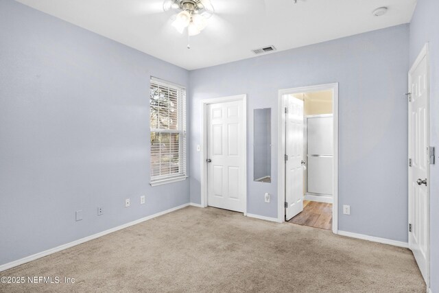 unfurnished bedroom featuring ensuite bath, carpet flooring, baseboards, and visible vents