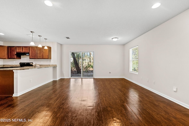 unfurnished living room featuring visible vents, baseboards, a healthy amount of sunlight, and dark wood-style flooring