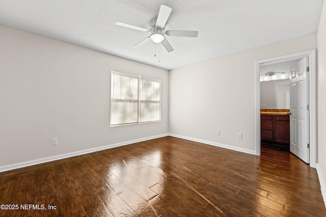 unfurnished room with ceiling fan, baseboards, dark wood-style flooring, and a textured ceiling