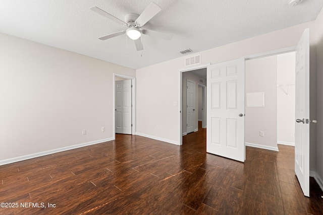 unfurnished bedroom featuring visible vents, a ceiling fan, a textured ceiling, wood finished floors, and baseboards