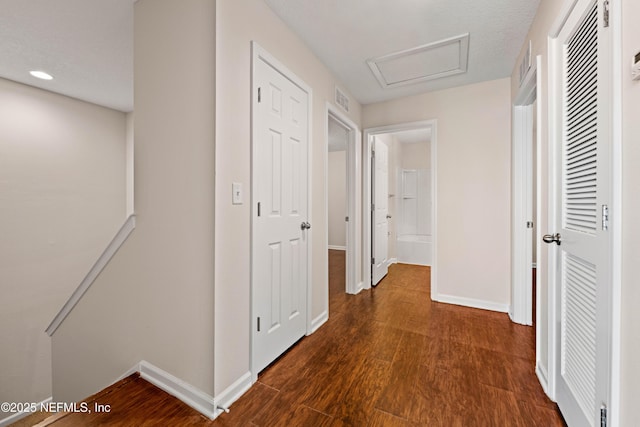 corridor with visible vents, an upstairs landing, baseboards, attic access, and dark wood-style flooring