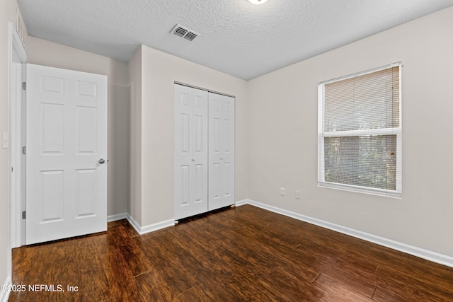 unfurnished bedroom featuring baseboards, visible vents, dark wood-style flooring, a closet, and a textured ceiling