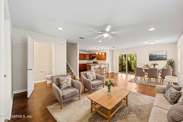 living area with stairway, recessed lighting, wood finished floors, and baseboards