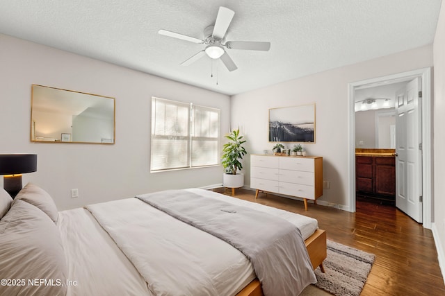 bedroom featuring ensuite bathroom, a textured ceiling, wood finished floors, baseboards, and ceiling fan