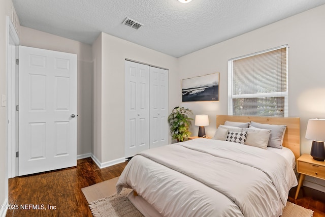 bedroom featuring visible vents, baseboards, wood finished floors, a closet, and a textured ceiling