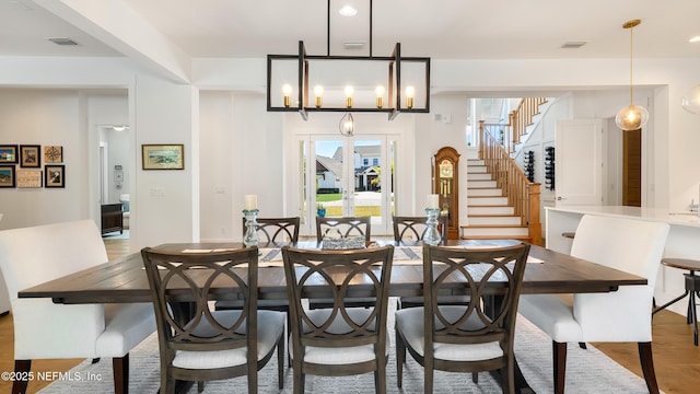 dining space featuring stairway, a notable chandelier, visible vents, and light wood finished floors