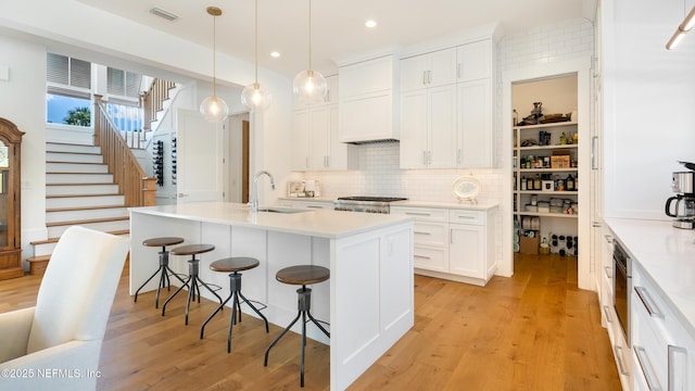 kitchen with light wood-style flooring, a sink, light countertops, stove, and a kitchen bar