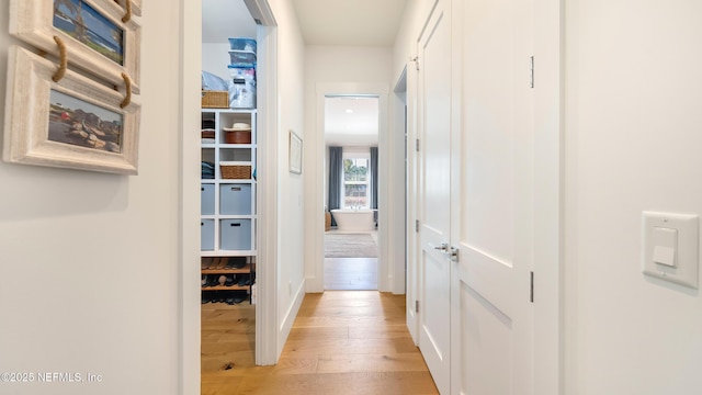 hall featuring light wood finished floors and baseboards