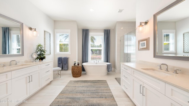 bathroom with a freestanding tub, wood finished floors, two vanities, and a sink