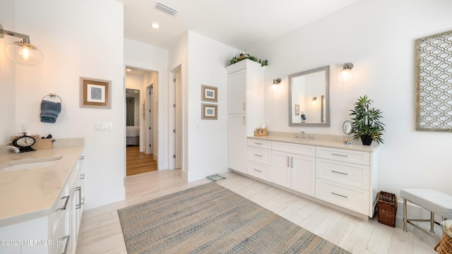 full bathroom with a sink, visible vents, two vanities, and wood finished floors