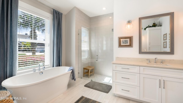 full bathroom with recessed lighting, a freestanding tub, vanity, and a shower stall