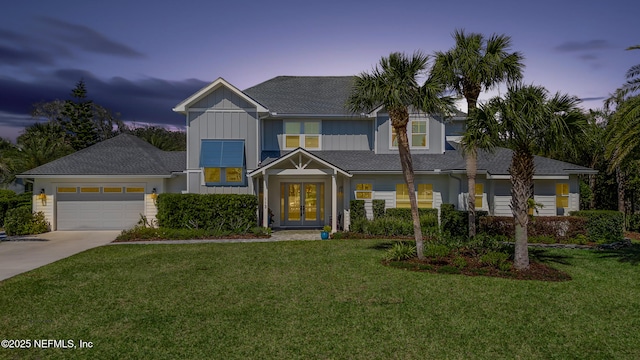 view of front facade with concrete driveway, a yard, french doors, and a garage