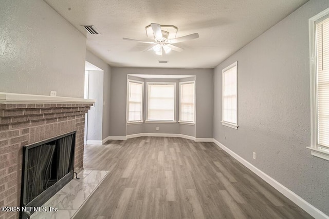 8027 Floyd St, Jacksonville, FL 32208 - unfurnished living room featuring a brick fireplace, wood finished floors, visible vents, and baseboards