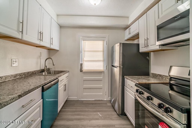 8027 Floyd St, Jacksonville, FL 32208 - kitchen featuring light wood finished floors, white cabinets, dark countertops, appliances with stainless steel finishes, and a sink