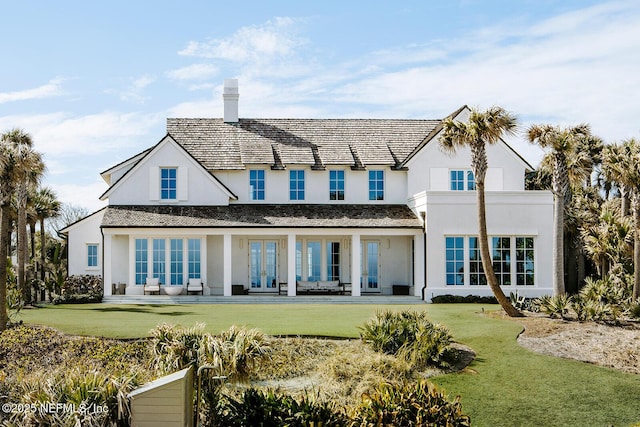 rear view of property featuring stucco siding, french doors, a lawn, and a patio