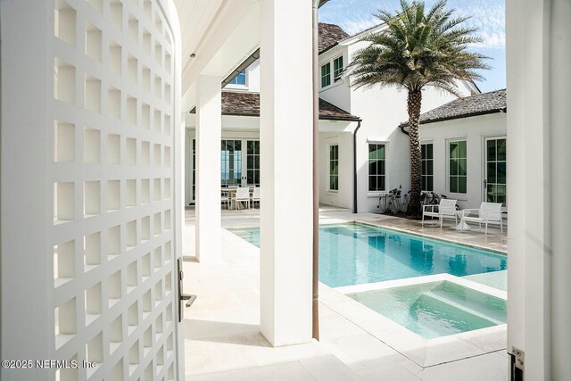 pool featuring an in ground hot tub and a patio area