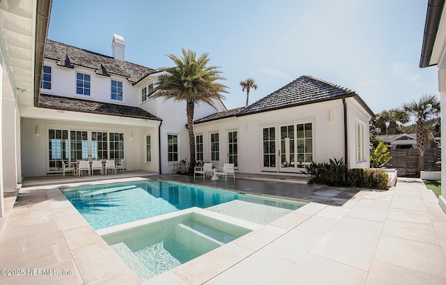 back of property featuring an in ground hot tub, french doors, a patio area, and an outdoor pool