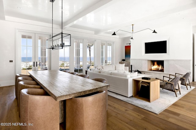 interior space with french doors, a lit fireplace, baseboards, and wood finished floors