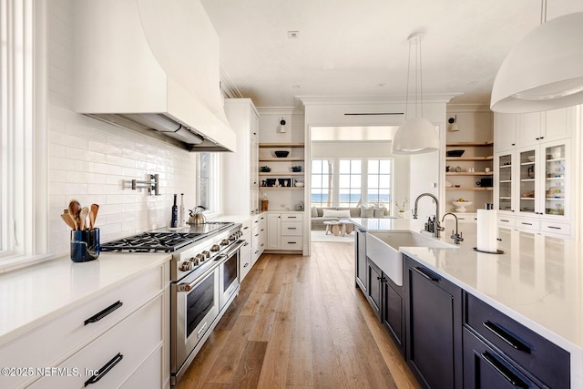 kitchen featuring open shelves, light wood-style floors, a sink, double oven range, and premium range hood