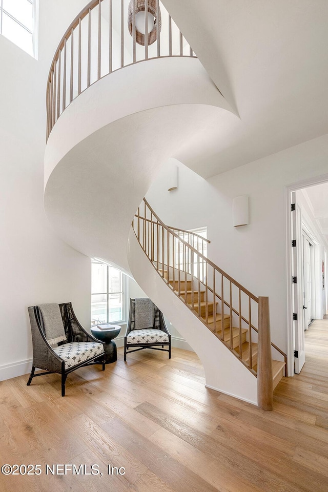 staircase with a towering ceiling, baseboards, and wood finished floors