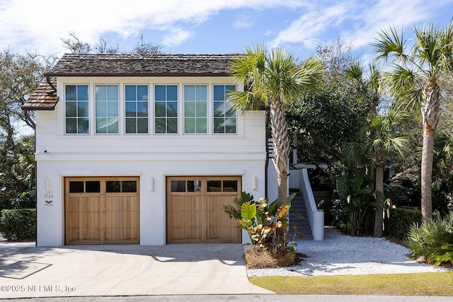 view of side of property featuring a garage, stucco siding, driveway, and stairs