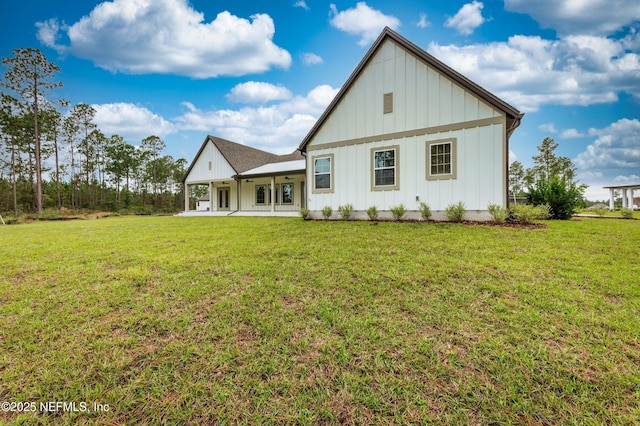 rear view of house featuring board and batten siding, a yard, and a patio