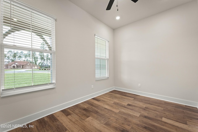 unfurnished room featuring dark wood-style floors, plenty of natural light, baseboards, and ceiling fan