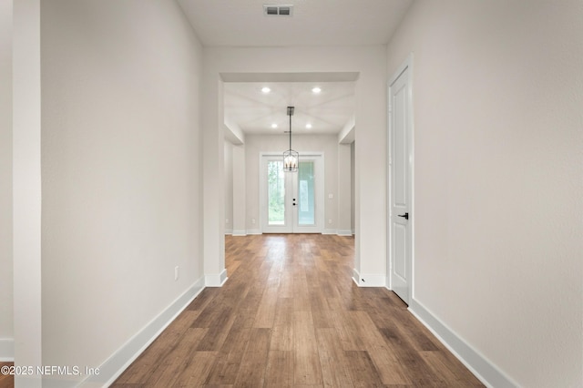 corridor with french doors, dark wood-type flooring, visible vents, and baseboards