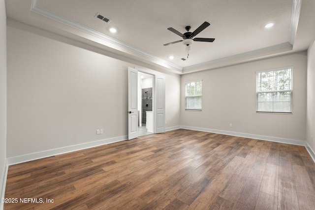 spare room featuring wood finished floors, a raised ceiling, visible vents, and crown molding