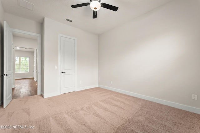 unfurnished bedroom featuring carpet floors, visible vents, baseboards, and a ceiling fan