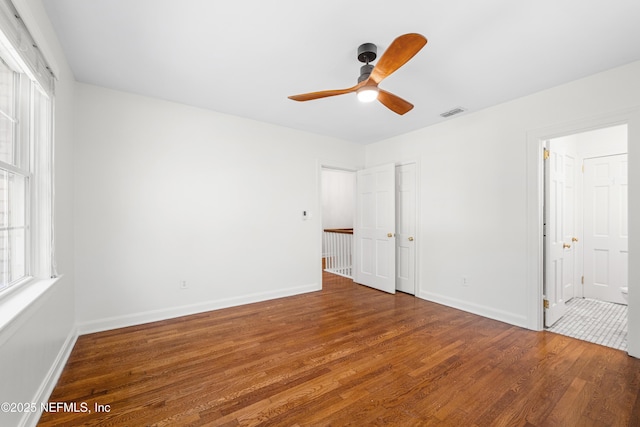 unfurnished bedroom with visible vents, ceiling fan, baseboards, and wood finished floors