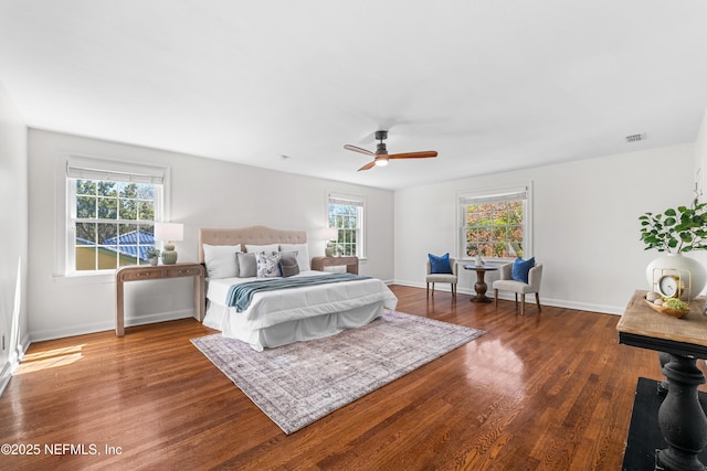 bedroom with multiple windows, baseboards, and wood finished floors