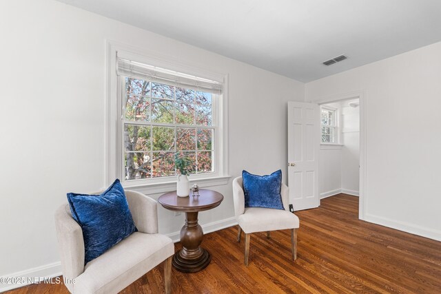 sitting room featuring baseboards, visible vents, and wood finished floors