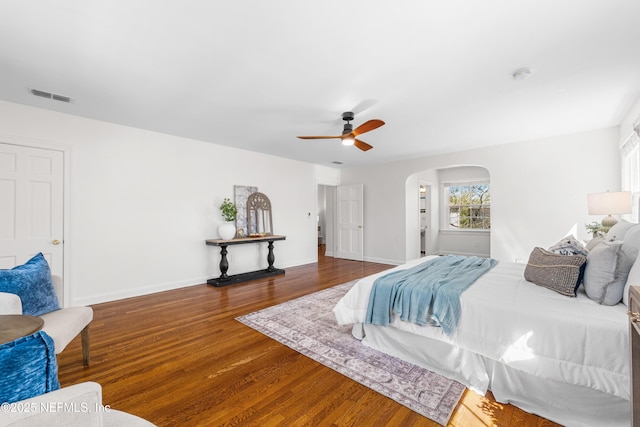 bedroom featuring baseboards, visible vents, arched walkways, and wood finished floors