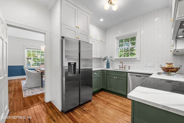 kitchen featuring light countertops, green cabinets, appliances with stainless steel finishes, light wood-style floors, and a sink