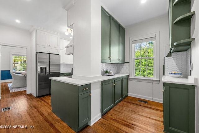 kitchen featuring dark wood-type flooring, stainless steel fridge, green cabinets, and light countertops