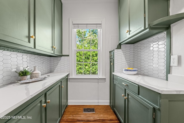 kitchen with backsplash, green cabinets, and wood finished floors