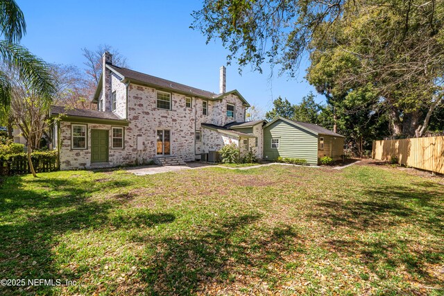 back of property featuring a patio, cooling unit, fence, a lawn, and a chimney