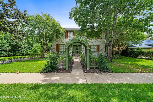 view of front of house with stone siding and a front lawn