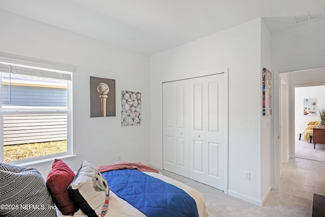 carpeted bedroom with a closet, visible vents, and baseboards