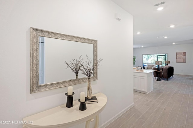 hallway featuring recessed lighting, visible vents, baseboards, and light wood-style flooring