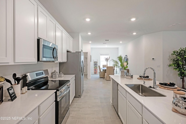 kitchen featuring recessed lighting, a sink, light countertops, white cabinets, and appliances with stainless steel finishes