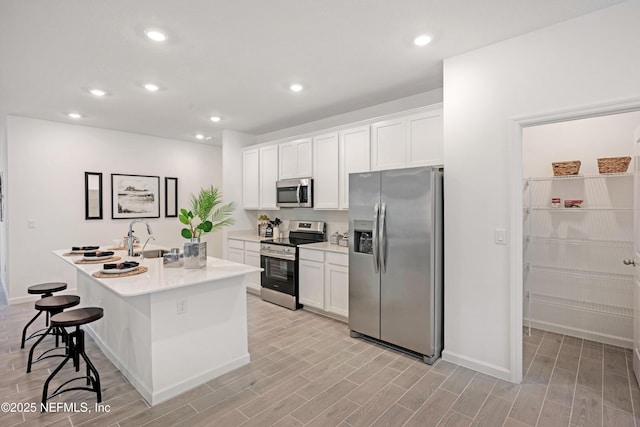 kitchen featuring appliances with stainless steel finishes, white cabinets, and wood tiled floor