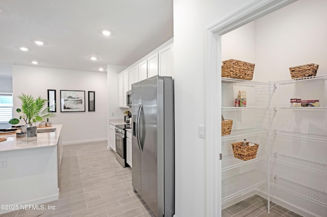 kitchen with recessed lighting, appliances with stainless steel finishes, white cabinets, light countertops, and baseboards