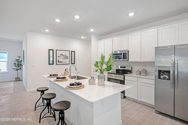 kitchen with white cabinetry, a kitchen island with sink, appliances with stainless steel finishes, and a sink