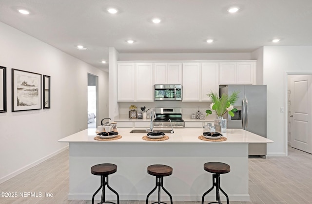 kitchen with white cabinetry, appliances with stainless steel finishes, a breakfast bar, and a sink