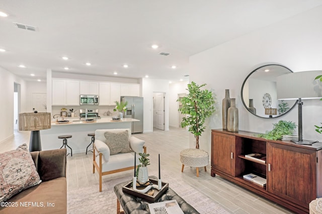 living area with recessed lighting, visible vents, and light wood-style flooring