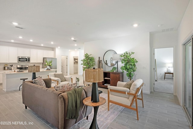 living area featuring visible vents, recessed lighting, and light wood-style floors