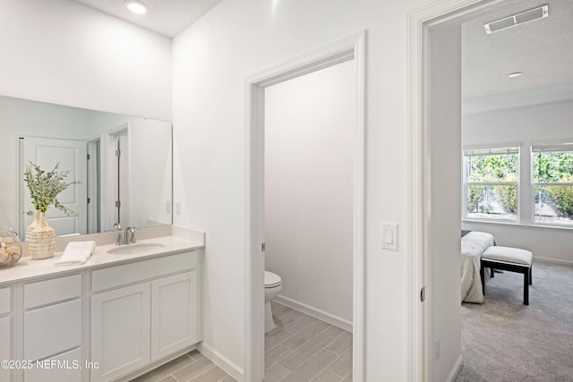 ensuite bathroom with visible vents, toilet, connected bathroom, baseboards, and vanity