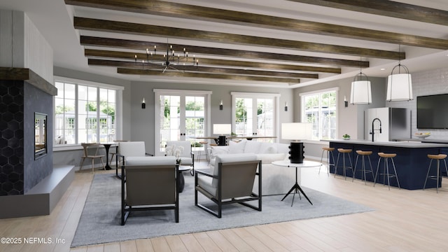 living area featuring beam ceiling, light wood-style flooring, a fireplace with raised hearth, and french doors